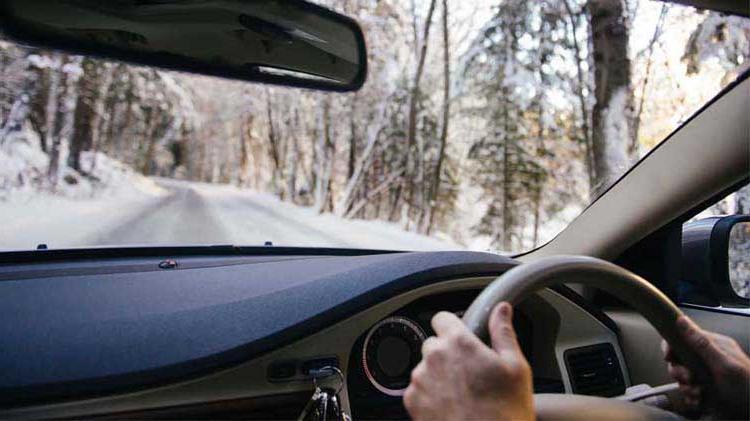 View looking out of car windshield while driving on a snowy road