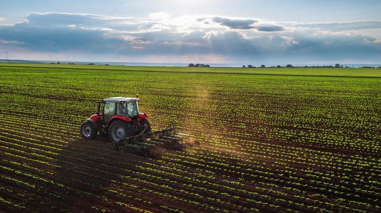 Tractor cultivating a field at spring, aerial view.