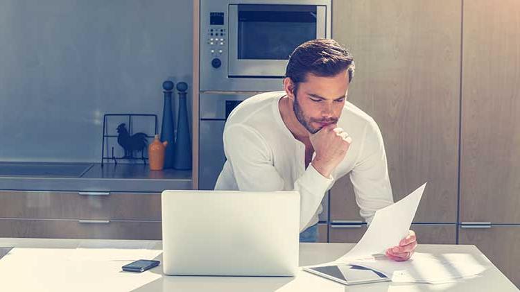 Gentlemen reading divorce paperwork in his kitchen.