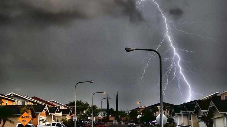 A lightning bolt flashing across the sky over a town.