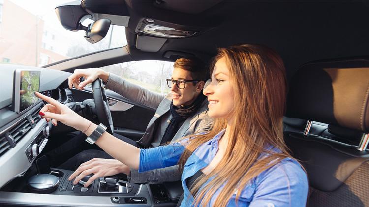 Driver using one of his car features, the onboard navigation system.