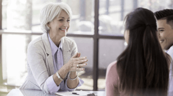 Insurance agent seated at a table talking to a man and woman.